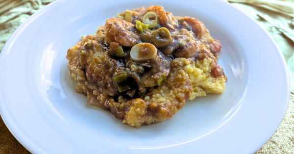 Southern-style shrimp and grits with vegetables and rich gravy on a white plate