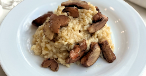 Creamy risotto topped with sautéed mushrooms served on a white plate
