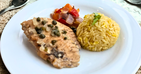 Chicken piccata topped with capers, served with yellow rice pilaf and sautéed vegetables