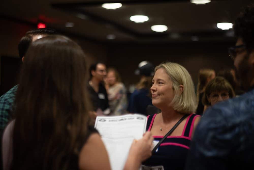 Woman smiling and engaging in character during a corporate murder mystery event in Greensboro, NC.