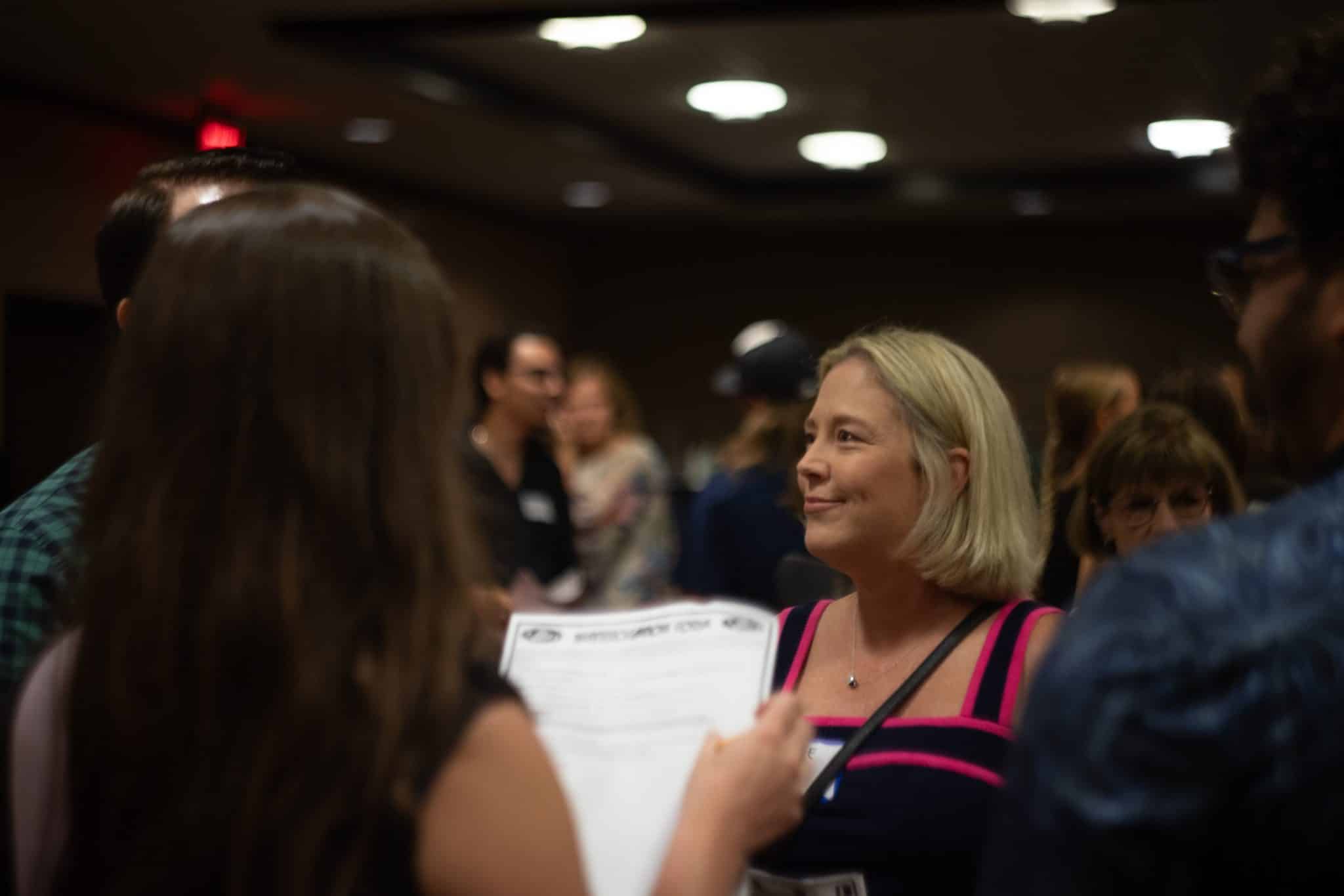 Woman smiling and engaging in character during a corporate murder mystery event in Greensboro, NC.