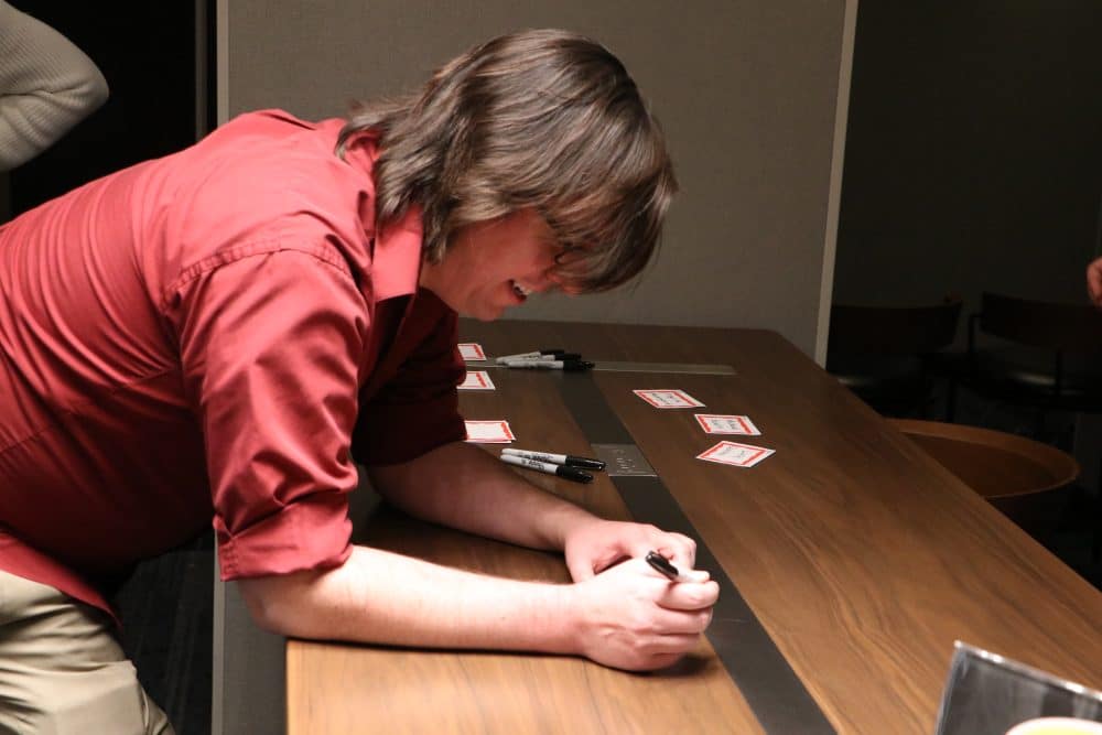 Person writing name tags for a corporate murder mystery dinner event in Greensboro, NC.