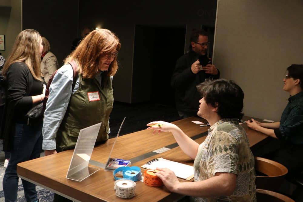 Guests receiving tickets and name tags at a corporate murder mystery dinner.