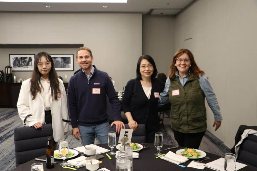 Group of attendees smiling around a dinner table before the murder mystery begins.