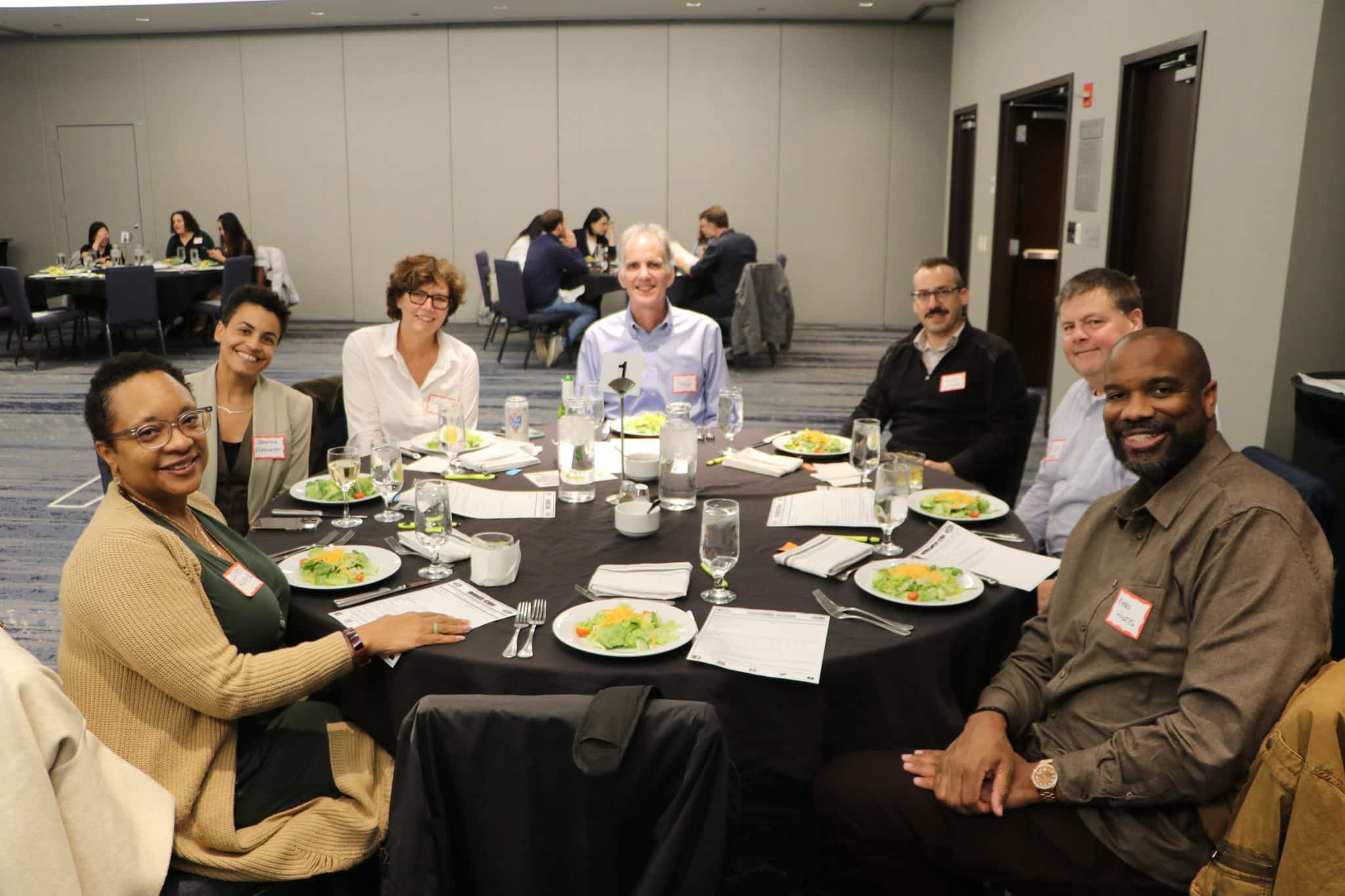 Corporate team smiling around a dinner table at The Dinner Detective event in Houston