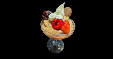 Gourmet dessert of chocolate mousse with fresh berries and a cream topping in a glass.
