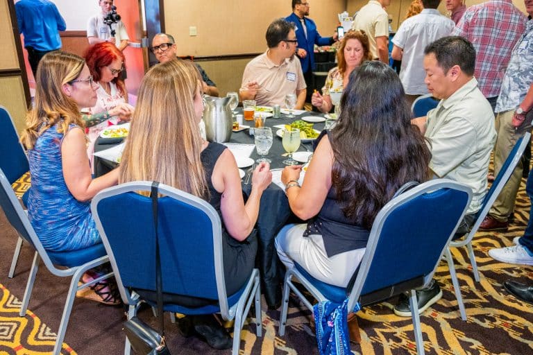 Guests enjoying a corporate murder mystery dinner at The Dinner Detective in Lexington, KY, while discussing clues over a meal.