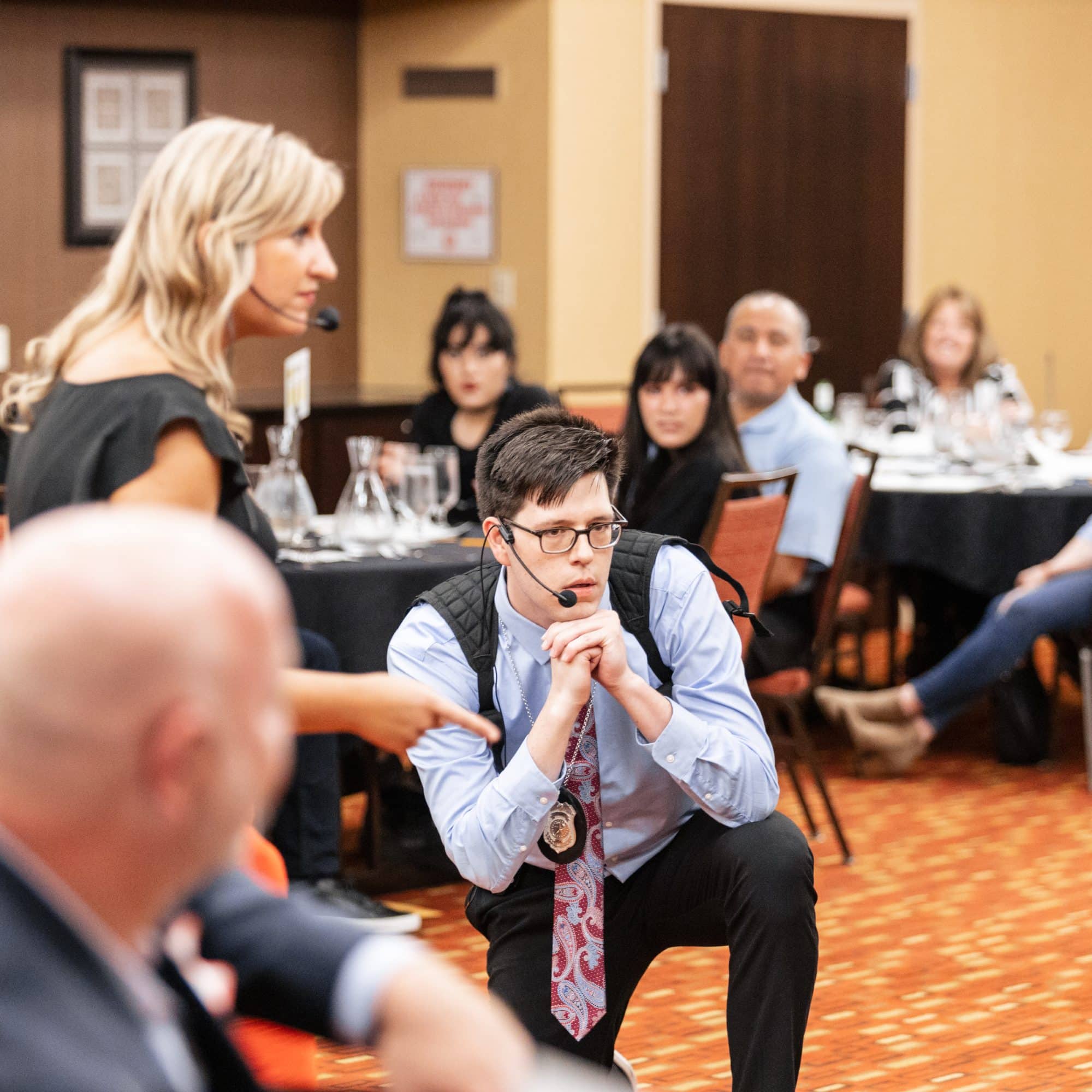 Actors leading an interactive corporate murder mystery dinner at The Dinner Detective Lexington, KY, with engaged audience participation.