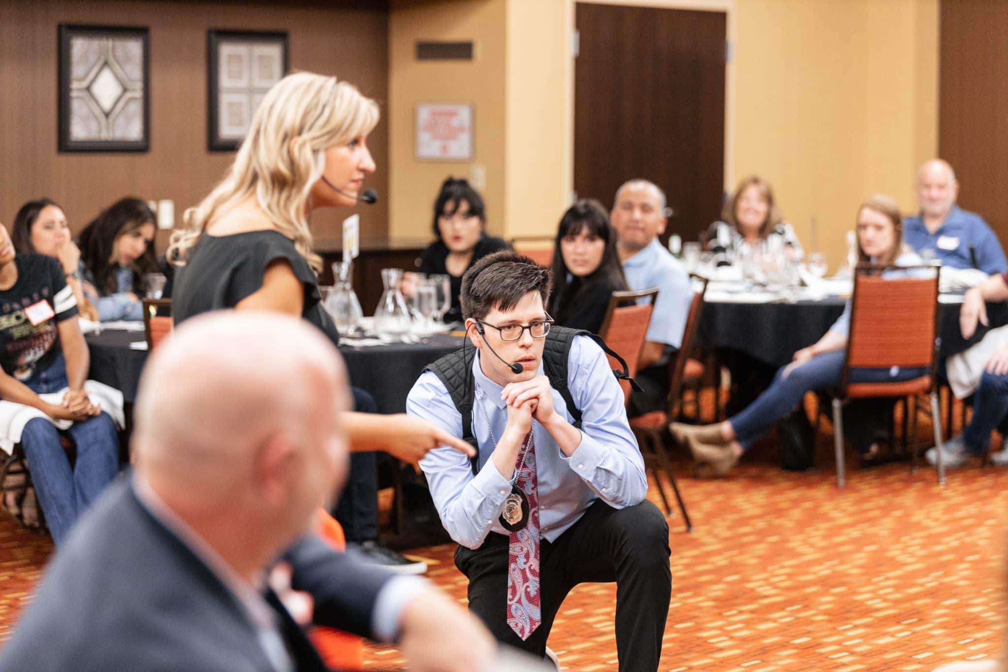 Actors leading an interactive corporate murder mystery dinner at The Dinner Detective Lexington, KY, with engaged audience participation.