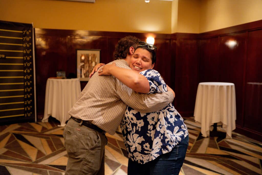 Two guests share a warm hug and smile in the lobby of The Dinner Detective show in Lexington, KY.