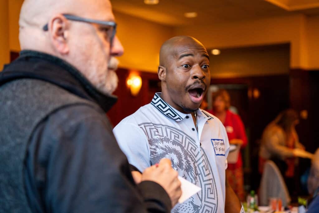 Man in a white patterned shirt making a surprised expression during a live Dinner Detective show in Lexington, KY.