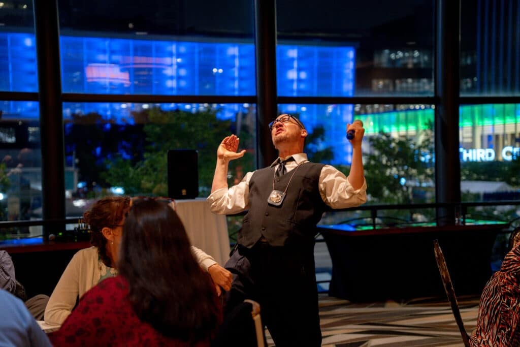 Detective character delivers a big laugh during a Lexington Dinner Detective show while guests react at nearby tables