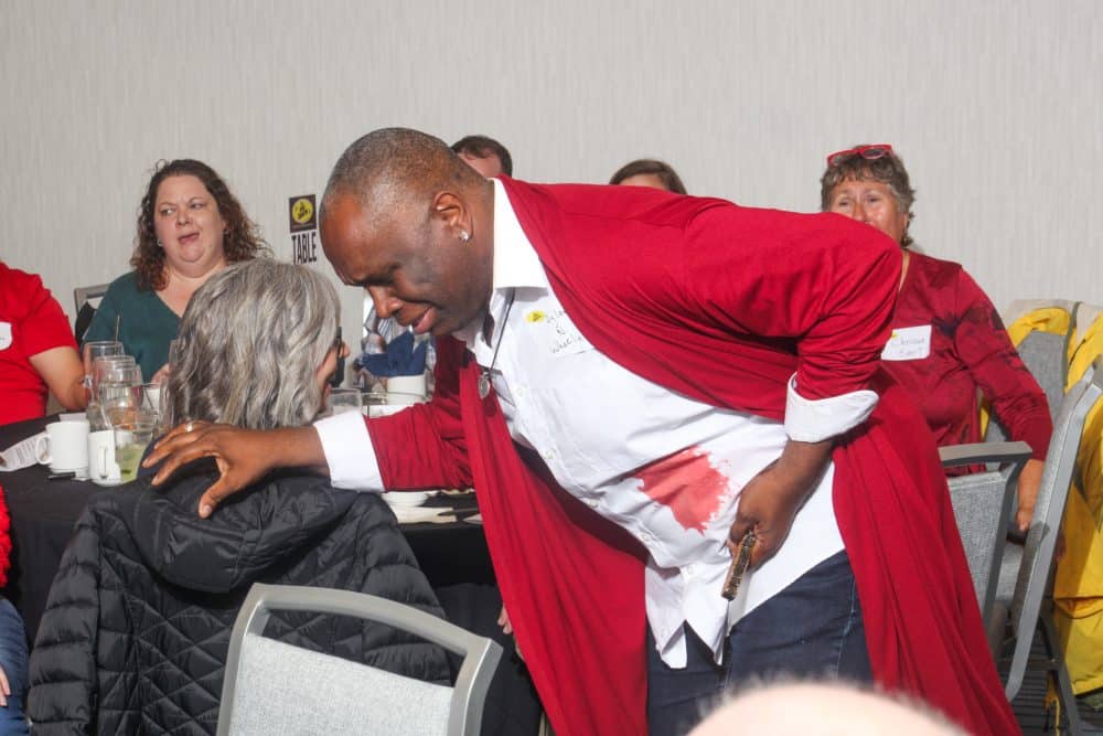 A man in a red robe clutches his side, pretending to be wounded during an interactive moment at The Dinner Detective Murder Mystery Show in Louisville.