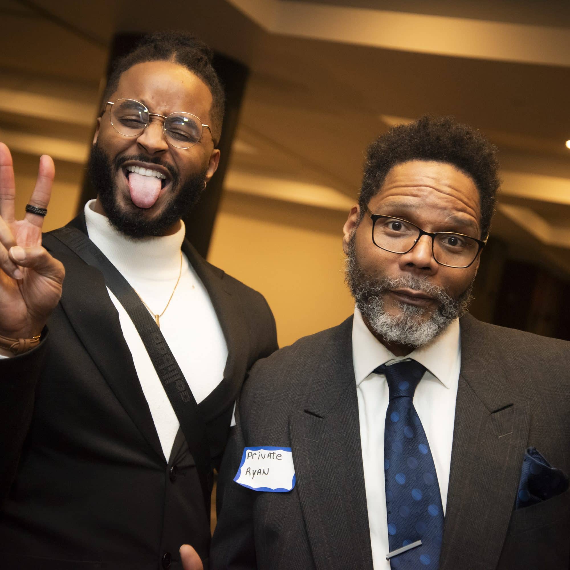 Two Dinner Detective performers posing in character; one making a peace sign and the other with a deadpan expression.
