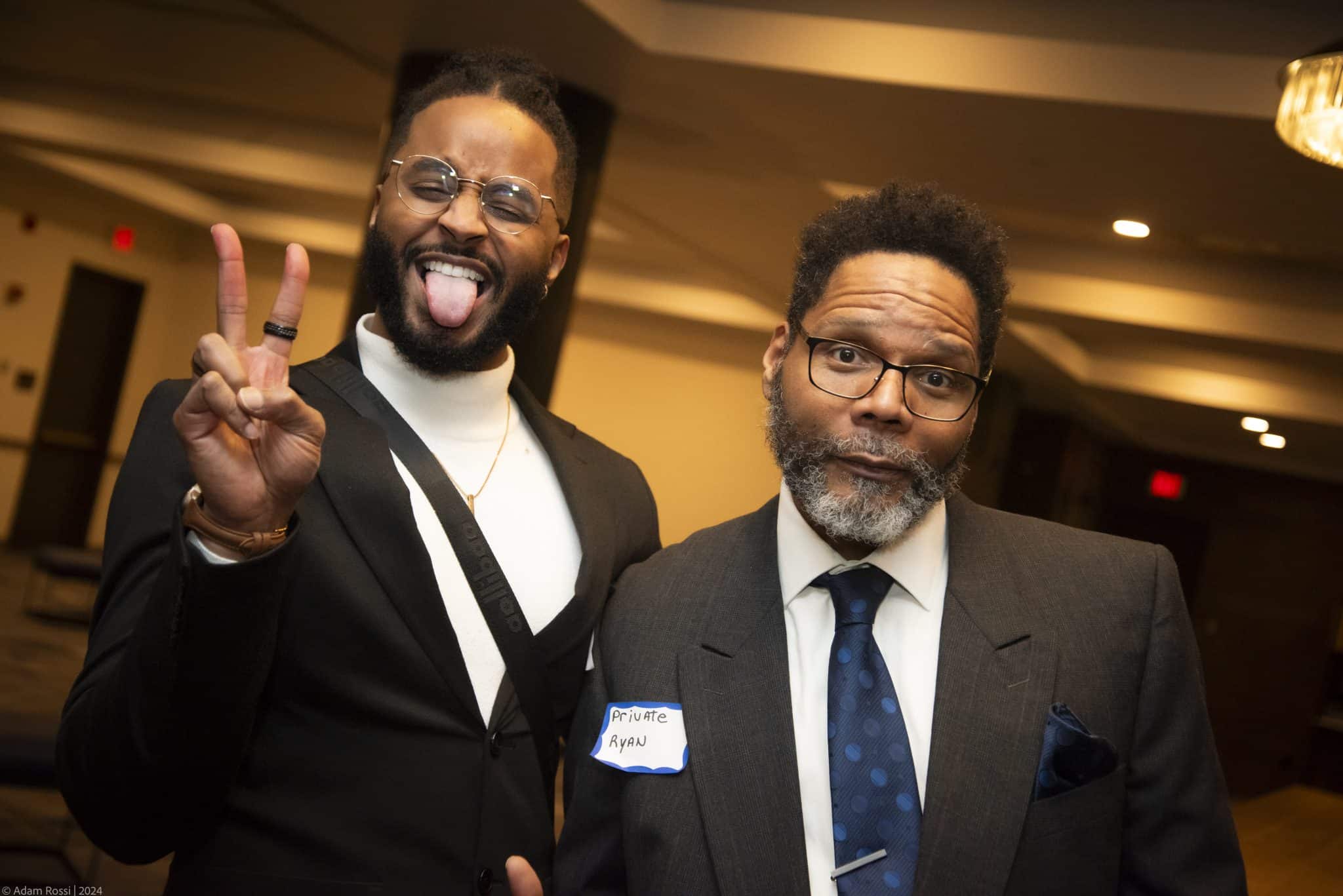 Two Dinner Detective performers posing in character; one making a peace sign and the other with a deadpan expression.