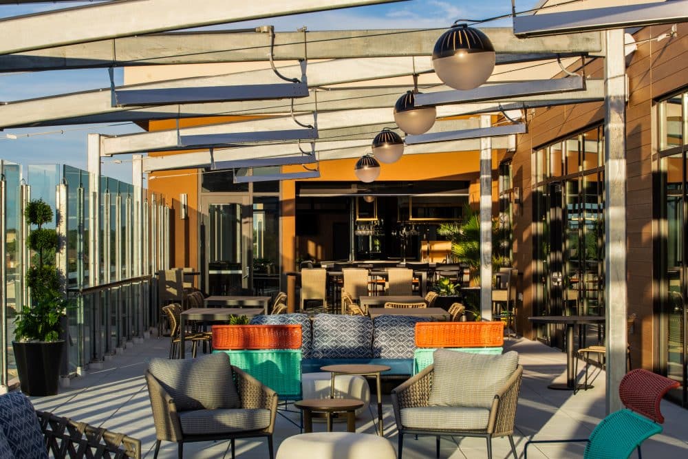 Rooftop lounge and bar area at Tempo by Hilton Louisville NuLu, featuring colorful seating and modern design.