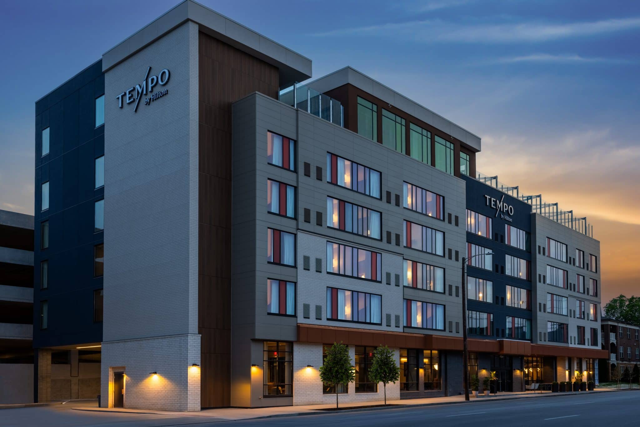 Exterior view of Tempo by Hilton in Louisville’s NuLu neighborhood at dusk, showcasing the modern architecture and rooftop venue.