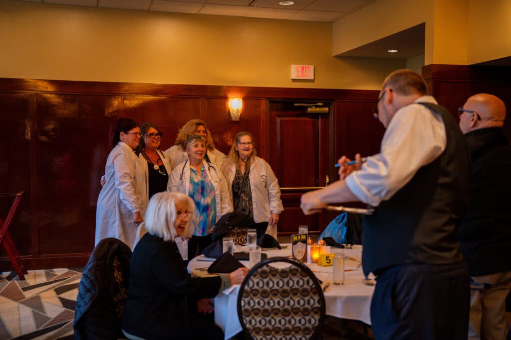 Group poses in costume during a private murder mystery dinner event at The Dinner Detective Louisville.