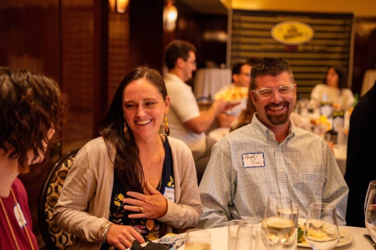 Couple laughing together at The Dinner Detective murder mystery dinner show in Phoenix, wearing name tags at their table