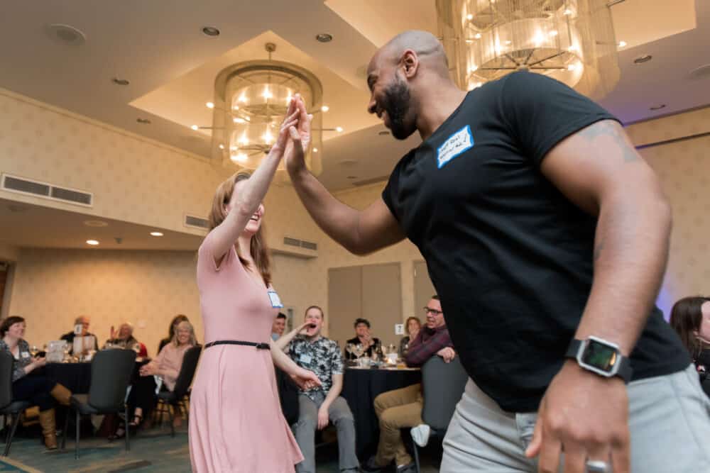 Two guests at a murder mystery dinner party giving each other a high-five in celebration.
