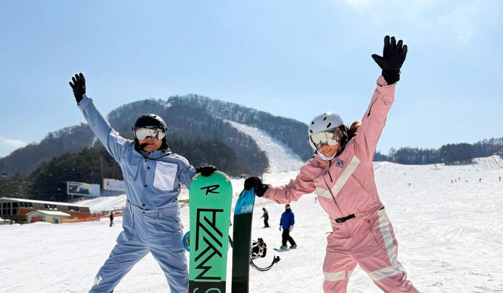 Two snowboarders in colorful gear celebrating on a snowy mountain slope, symbolizing excitement and achievement