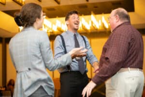 Guests laugh with a detective actor during an interactive moment at The Dinner Detective Father’s Day show in Salt Lake City.