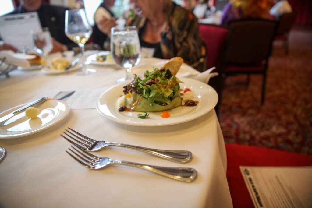 Fresh salad course at an interactive dinner show in downtown Salt Lake City with guests mingling at candlelit tables