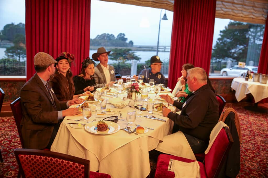Guests gathered around a round table at an interactive dinner show in Salt Lake City discussing clues between courses