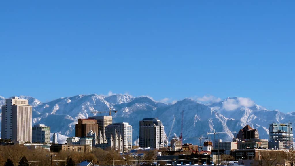 A wide view of the Salt Lake City skyline against the snow-capped Wasatch Mountains, illustrating the unpredictable weather that makes indoor activities Salt Lake so popular.