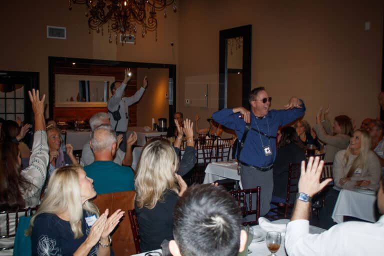 Guests laugh and raise hands during an interactive murder mystery dinner show in San Diego - a unique thing to do at night