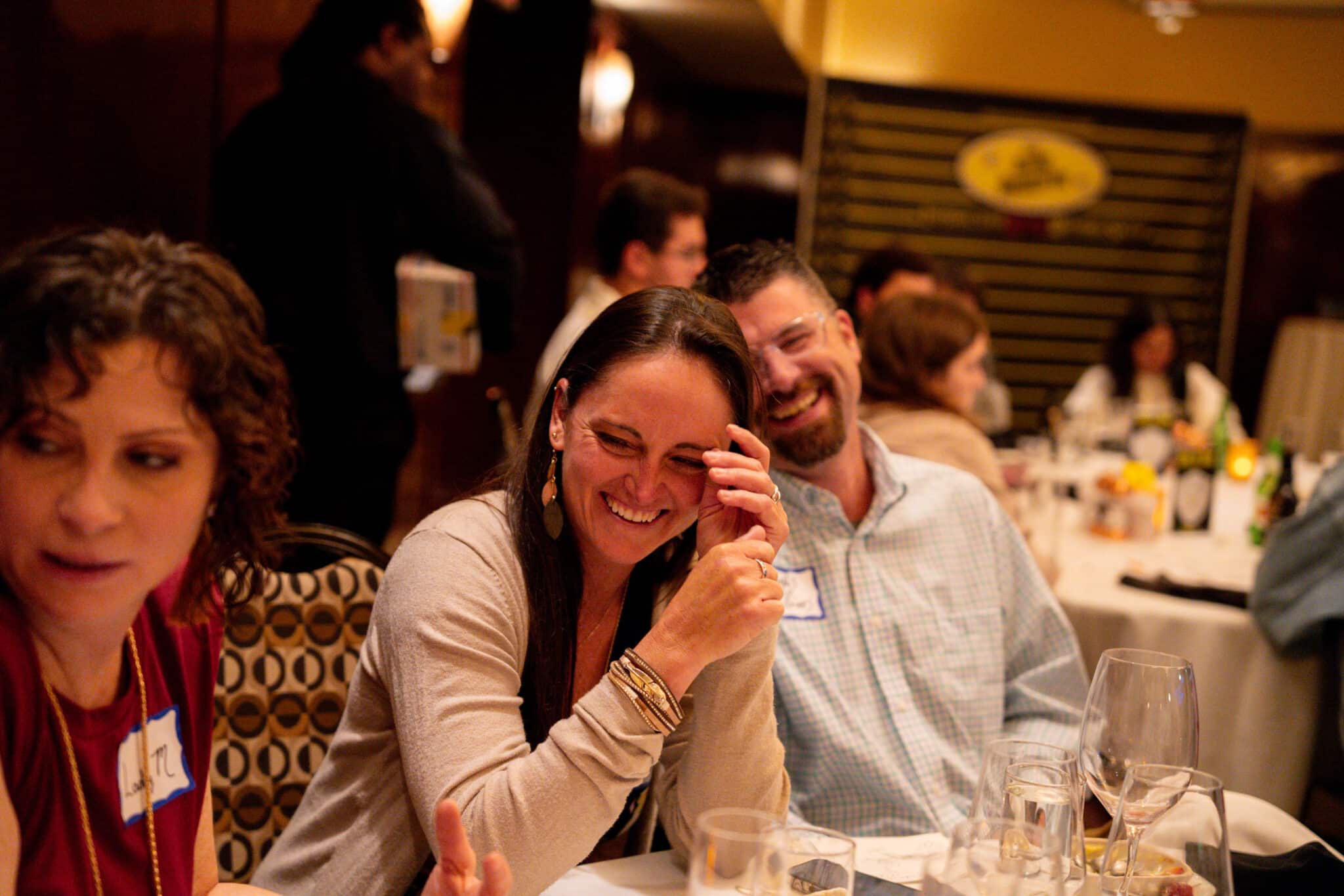 Guests laughing and enjoying a mystery dinner show in a warmly lit Seattle venue during the holiday season.