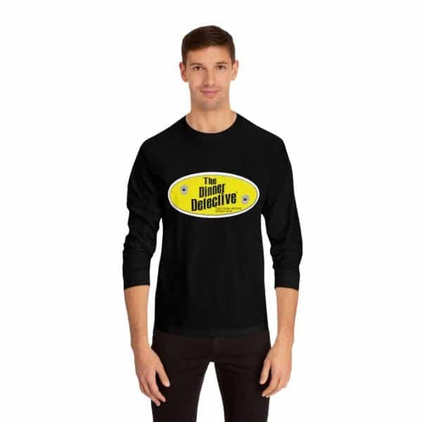 A person wears a Unisex Classic Long Sleeve T-Shirt in black with The Dinner Detective logo in yellow and white. It features ribbed cuffs and offers a classic fit, set against a plain white background that highlights its timeless appeal.