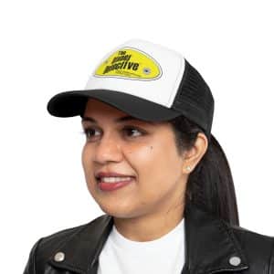 A person in a Mesh Cap featuring a yellow logo, along with a white shirt and a black leather jacket, stands against a white background.