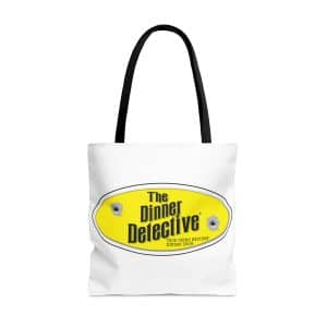 White tote bag with black handles featuring a yellow oval logo that reads The Dinner Detective in bold black letters, complete with two bullet hole graphics. Below the main logo, text says Americas Largest Interactive Murder Mystery Dinner Show.