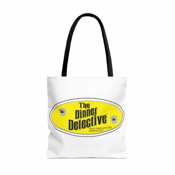 White tote bag with black handles featuring a yellow oval logo that reads The Dinner Detective in bold black letters, complete with two bullet hole graphics. Below the main logo, text says Americas Largest Interactive Murder Mystery Dinner Show.